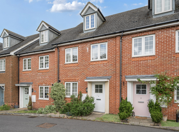 Red brick mid-terrace house with white doors and dark slated roof.