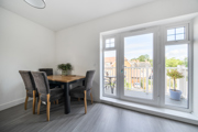 Dining area with table and chairs beside glass doors leading to balcony.