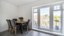 Dining area with table and chairs beside glass doors leading to balcony.