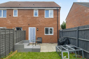 Rear view of brick house with patio, lawn, and fenced garden.
