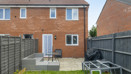 Rear view of brick house with patio, lawn, and fenced garden.