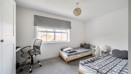Bedroom with two single beds, study desk, office chair and window.