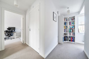 Hallway with white doors, bookcase and adjoining study area.