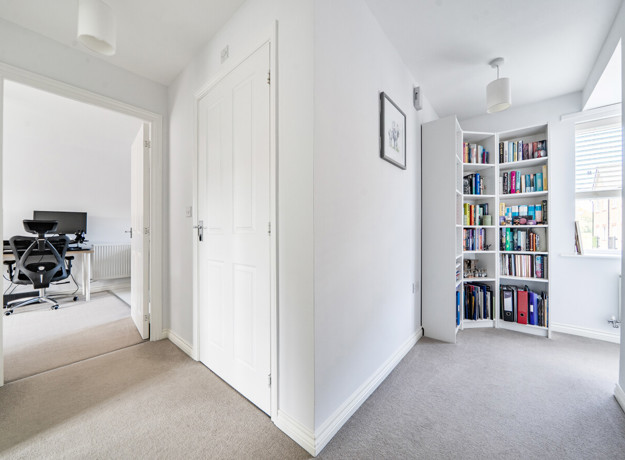 Hallway with white doors, bookcase and adjoining study area.