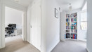 Hallway with white doors, bookcase and adjoining study area.