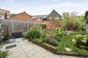 Rear garden with patio, planted borders, fencing and outdoor seating.