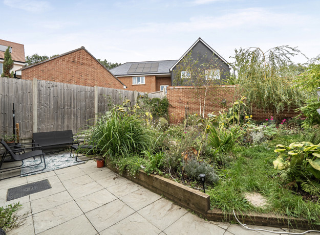 Rear garden with patio, planted borders, fencing and outdoor seating.