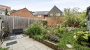 Rear garden with patio, planted borders, fencing and outdoor seating.
