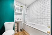 Bathroom with bath, shower, toilet, wash basin and tiled walls.