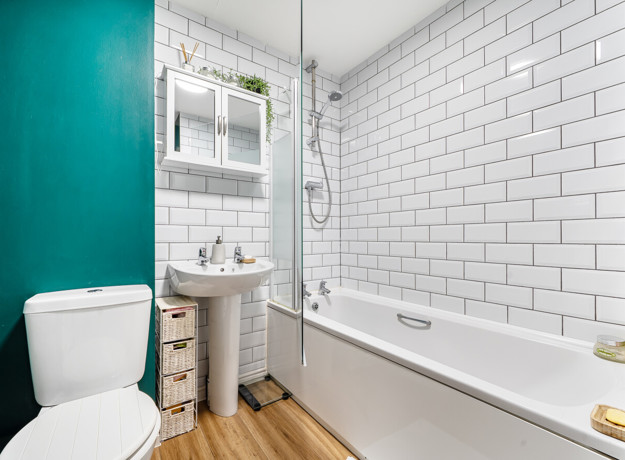Bathroom with bath, shower, toilet, wash basin and tiled walls.