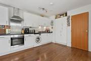 White kitchen with oven, washing machine, cabinets, and wooden floor.
