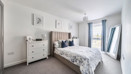 Bedroom with double bed, chest of drawers and windows with curtains.