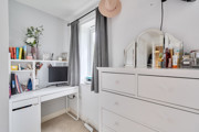 Room with white dresser, mirror, desk and shelving unit beside a window.