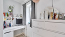 Room with white dresser, mirror, desk and shelving unit beside a window.