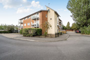 Apartment building with parking spaces, trees and surrounding pathways.