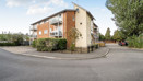 Apartment building with parking spaces, trees and surrounding pathways.
