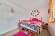 Bedroom with a single bed, colourful bedding, neutral décor, and window providing natural light.