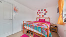 Bedroom with a single bed, colourful bedding, neutral décor, and window providing natural light.