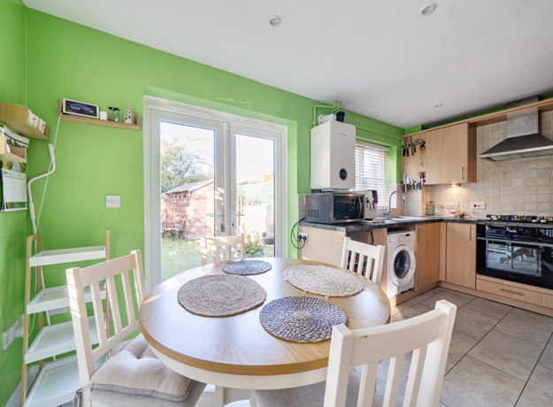 Kitchen and diner with round table, chairs and patio doors to the garden.