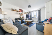 Living room with sofas, coffee table, TV, shelving units and window with curtains.