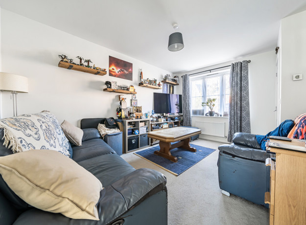 Living room with sofas, coffee table, TV, shelving units and window with curtains.
