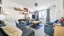 Living room with sofas, coffee table, TV, shelving units and window with curtains.