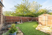 Garden with lawn, paved patio, wooden shed and surrounding fencing. (1)