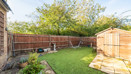 Garden with lawn, paved patio, wooden shed and surrounding fencing. (1)