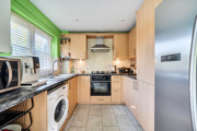Fitted kitchen with integrated oven, hob and window above the sink.