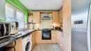 Fitted kitchen with integrated oven, hob and window above the sink.
