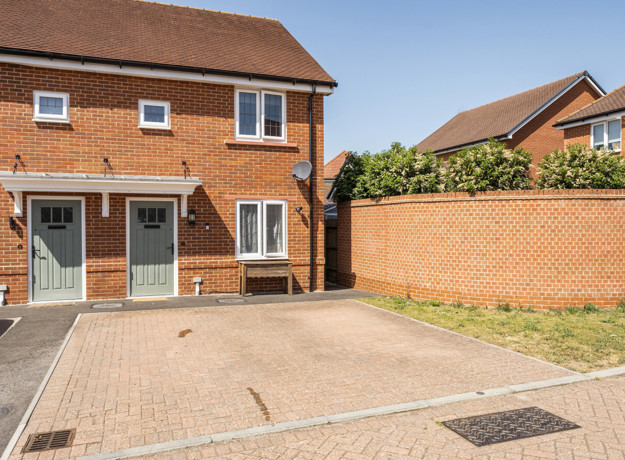Semi detached brick house with white windows, green front door and driveway