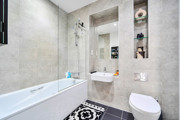 Bathroom with shower over bath, sink, toilet and bathmat on the floor.