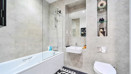 Bathroom with shower over bath, sink, toilet and bathmat on the floor.
