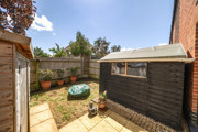 Paved garden area with fencing, shed and small seating space.