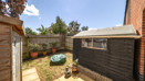 Paved garden area with fencing, shed and small seating space.