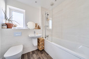 Bathroom with bath, shower, toilet, sink and frosted window.
