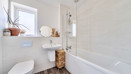 Bathroom with bath, shower, toilet, sink and frosted window.
