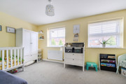 Nursery room with cot, storage units, yellow walls and window.