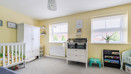 Nursery room with cot, storage units, yellow walls and window.