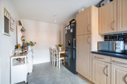 Kitchen with fitted units, dining table, shelving and appliances.