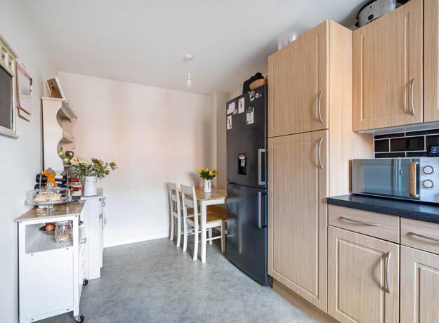 Kitchen with fitted units, dining table, shelving and appliances.