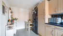 Kitchen with fitted units, dining table, shelving and appliances.