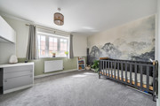 Bedroom with cot, chest of drawers, window and feature wall.
