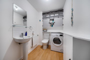 Utility room with sink, washing machine, storage shelves and worktop.