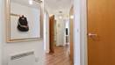 Hallway with wooden floor, framed wall art, doors, and wall heater.