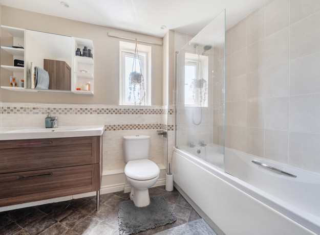 Bathroom with a bathtub, toilet, sink and mirrored cabinet.