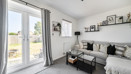 Living room with patio doors, a sofa and framed photos on the wall.