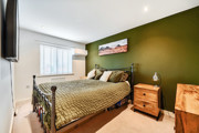 Bedroom with green feature wall, double bed, bedside tables and window.
