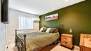 Bedroom with green feature wall, double bed, bedside tables and window.