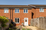 Rear view of a red brick house with patio doors and enclosed garden.